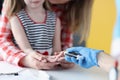 Doctor measuring blood glucose level of little girl with glucometer closeup