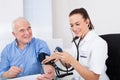 Doctor measuring blood pressure of senior man Royalty Free Stock Photo