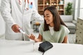 Doctor measuring glucose to latin woman at clinic