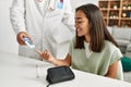 Doctor measuring glucose to latin woman at clinic