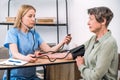 Doctor measuring high blood pressure to elderly patient in clinic Royalty Free Stock Photo