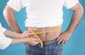 Doctor measuring overweight man`s waist on color background Royalty Free Stock Photo