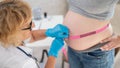 Doctor measuring the volume of a pregnant woman& x27;s abdomen using a centimeter tape. Royalty Free Stock Photo