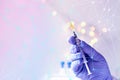 Doctor, medic holds in hand a thin syringe for intramuscular injection on a technological blue background, prepares to do