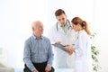 Doctor and medical assistant working with elderly patient