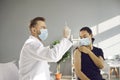 Doctor in medical face mask preparing syringe before giving injection to patient Royalty Free Stock Photo