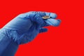 A doctor in a medical glove tosses a coin against a scarlet background. Concept to be or not