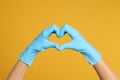 Doctor in medical gloves showing heart with hands on yellow background Royalty Free Stock Photo