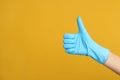 Doctor in medical gloves showing thumb up on yellow background, closeup. Space for text Royalty Free Stock Photo