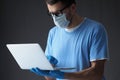 Doctor in medical mask and gloves works in laptop.