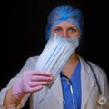 Doctor with a medical mask in his hand, closeup. Nurse gives face masks on a black background. Coronavirus pandemic protective