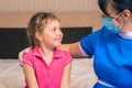 Doctor in a medical mask hugs a little girl. A nurse talking to a child about vaccination. The baby is smiling at the woman doctor