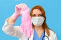 Doctor in a medical mask with protective gloves in hand on a blue background, portrait Royalty Free Stock Photo