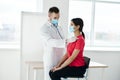 a doctor in a medical mask stands next to a woman in a red t-shirt chest examination breathing lungs covid Royalty Free Stock Photo