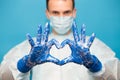 Doctor in medical suit protective mask and gloves, show heart symbol with hand in soap foam isolated on blue background. Hands Royalty Free Stock Photo