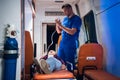 Doctor in uniform puts oxygen mask on woman lying on stretcher in the ambulance car