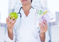 Doctor mid section with apple and money against blurry buildings Royalty Free Stock Photo