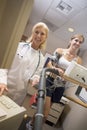 Doctor Monitoring Female Patient On Treadmill