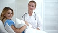 Doctor and mother holding newborn child smiling at camera, skin-to-skin contact