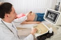 Doctor Moving Ultrasound Transducer On Pregnant Woman Belly