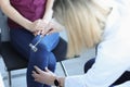 Doctor neurologist checking knee reflexes to female patient with percussion hammer in clinic closeup Royalty Free Stock Photo