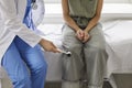 Doctor neurologist examining female patient knocking on knee with hammer in clinic closeup. Royalty Free Stock Photo