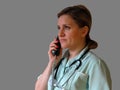 Doctor or nurse call by phone. Woman in uniform with handset and stethoscope around neck speaks