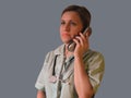 Doctor or nurse call by phone. Woman in uniform with handset and stethoscope around neck speaks