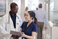 Doctor And Nurse Consulting Over Digital Tablet In Busy Hospital Corridor Royalty Free Stock Photo