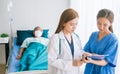 Doctor and nurse doing in a room at hospital and visiting a patient updating patient`s medical report.