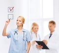 Doctor or nurse drawning checkmark into checkbox Royalty Free Stock Photo