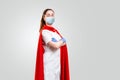 A doctor or nurse in medical gloves, mask and a red superhero Cape on a gray background. Medical personnel during a coronavirus Royalty Free Stock Photo