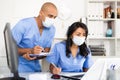 Doctor and nurse in protective medical mask check patient data in hospital computer Royalty Free Stock Photo