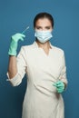 Doctor or nurse in protective medical mask holding syringe on blue background, medicine, safety and vaccination concept Royalty Free Stock Photo