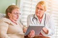 Helpful Doctor or Nurse Talking to Senior Woman with Touch Pad Computer