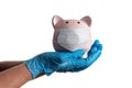 Doctor or Nurse Wearing Surgical Gloves Holding Piggy Bank Wearing Medical Face Mask Isolated on White