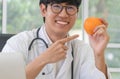 Doctor or nutritionist hold orange and Point your finger at the orange. in and smile in clinic. Healthy diet. Concept of nutrition Royalty Free Stock Photo