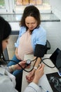 Doctor obstetrician gynecologist checking blood pressure of pregnant woman with tonometer during pregnancy consultation