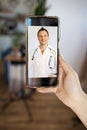 Doctor Online Via Video Call On Smartphone Sitting At Home. Physician Consulting Patient From Cellphone Screen. Distance Consultat