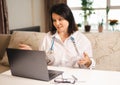 Doctor online. woman consults a patient, Doctor talking actively on video call remotely at home. doctor with stethoscope provides Royalty Free Stock Photo