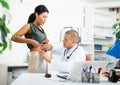 Doctor palpating abdomen of female patient in medical office