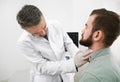 Doctor in medical gloves palpating man`s neck.