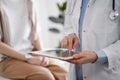 Doctor and patient in clinic. Friendly physician using tablet computer near a young woman. Medicine concept