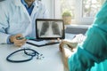 Doctor and patient discuss chest x-ray results on digital tablet in clinics office Royalty Free Stock Photo