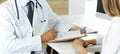 Doctor and patient discussing medical exam results while sitting at the desk in clinic, close-up. Male physician using Royalty Free Stock Photo