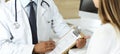 Doctor and patient discussing medical exam results while sitting at the desk in clinic, close-up. Male physician using Royalty Free Stock Photo