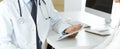 Doctor and patient discussing medical exam results while sitting at the desk in clinic, close-up. Male physician using Royalty Free Stock Photo