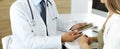 Doctor and patient discussing medical exam results while sitting at the desk in clinic, close-up. Male physician using Royalty Free Stock Photo