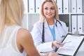 Doctor and patient discussing something while physician pointing into medical history form at clipboard