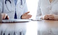 Doctor and patient discussing something while using laptop computer and sitting near each other at the wooden desk in Royalty Free Stock Photo